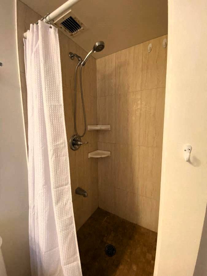 A white shower curtain hangs in a small bathroom.